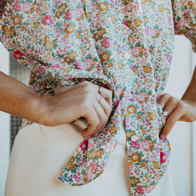 Person wearing a floral dress with their hands in front of them.