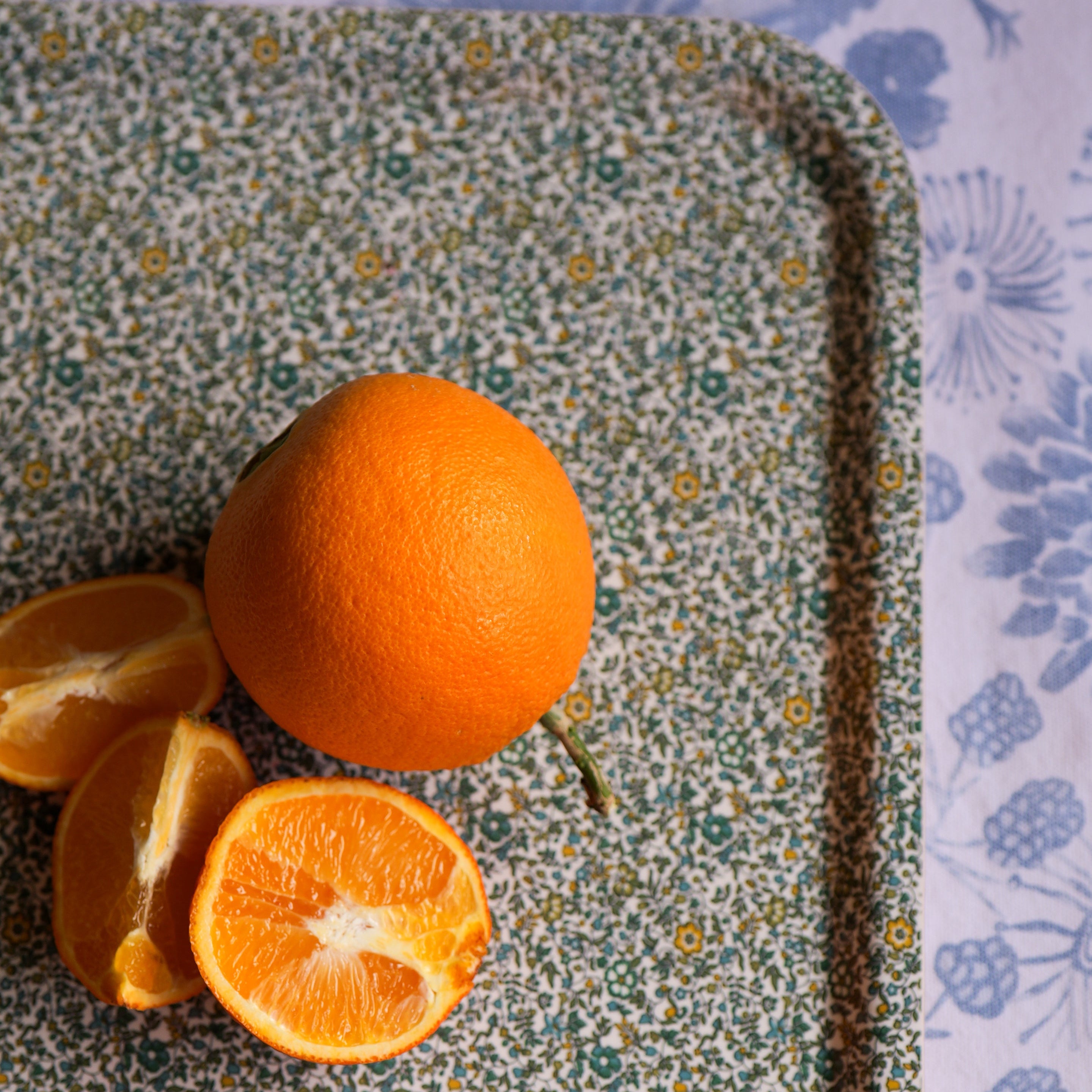 Oranges on a floral-patterned tray with a floral background