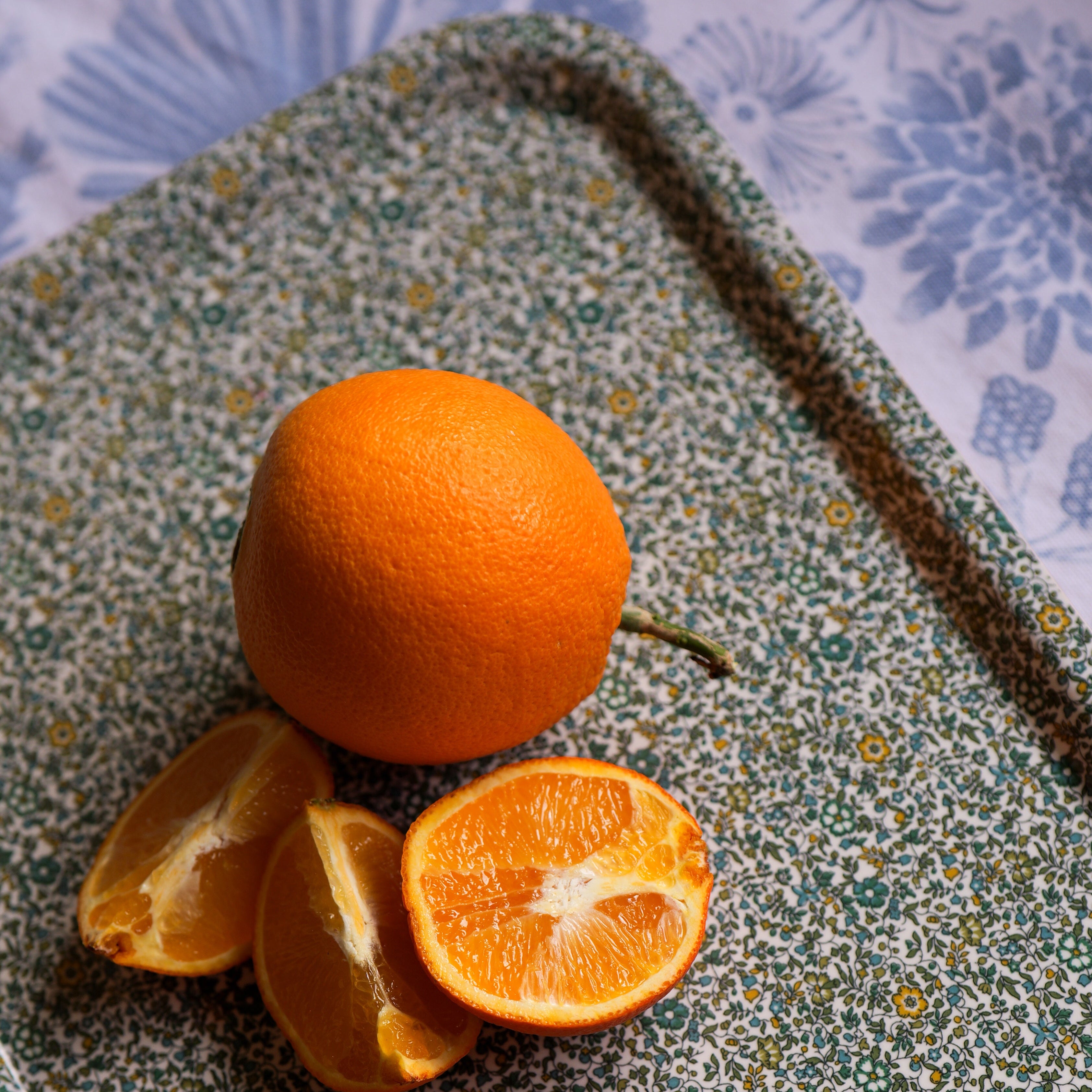 Oranges on a floral-patterned tray with a blue floral background