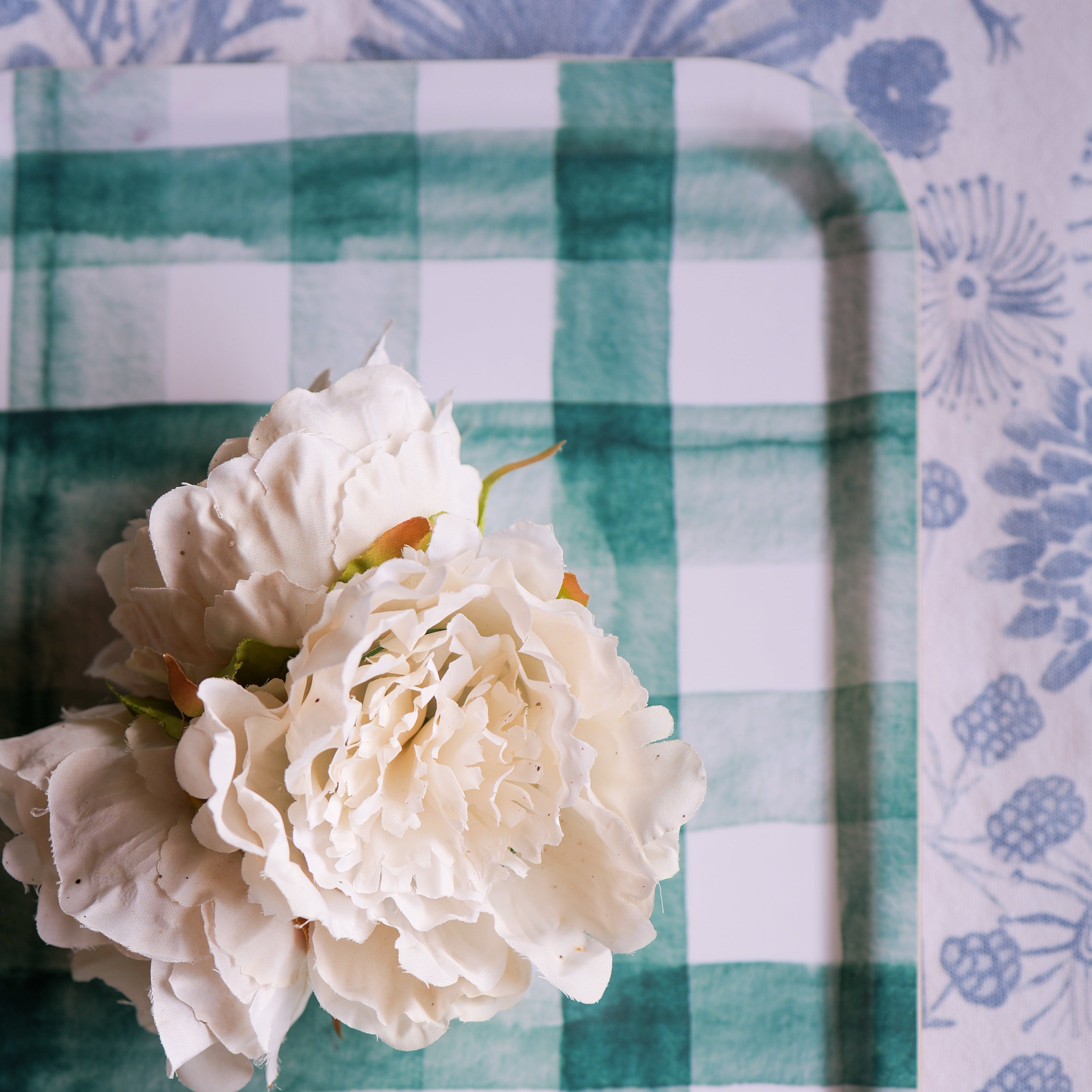 White flowers on a green and white checkered tray with a floral-patterned background