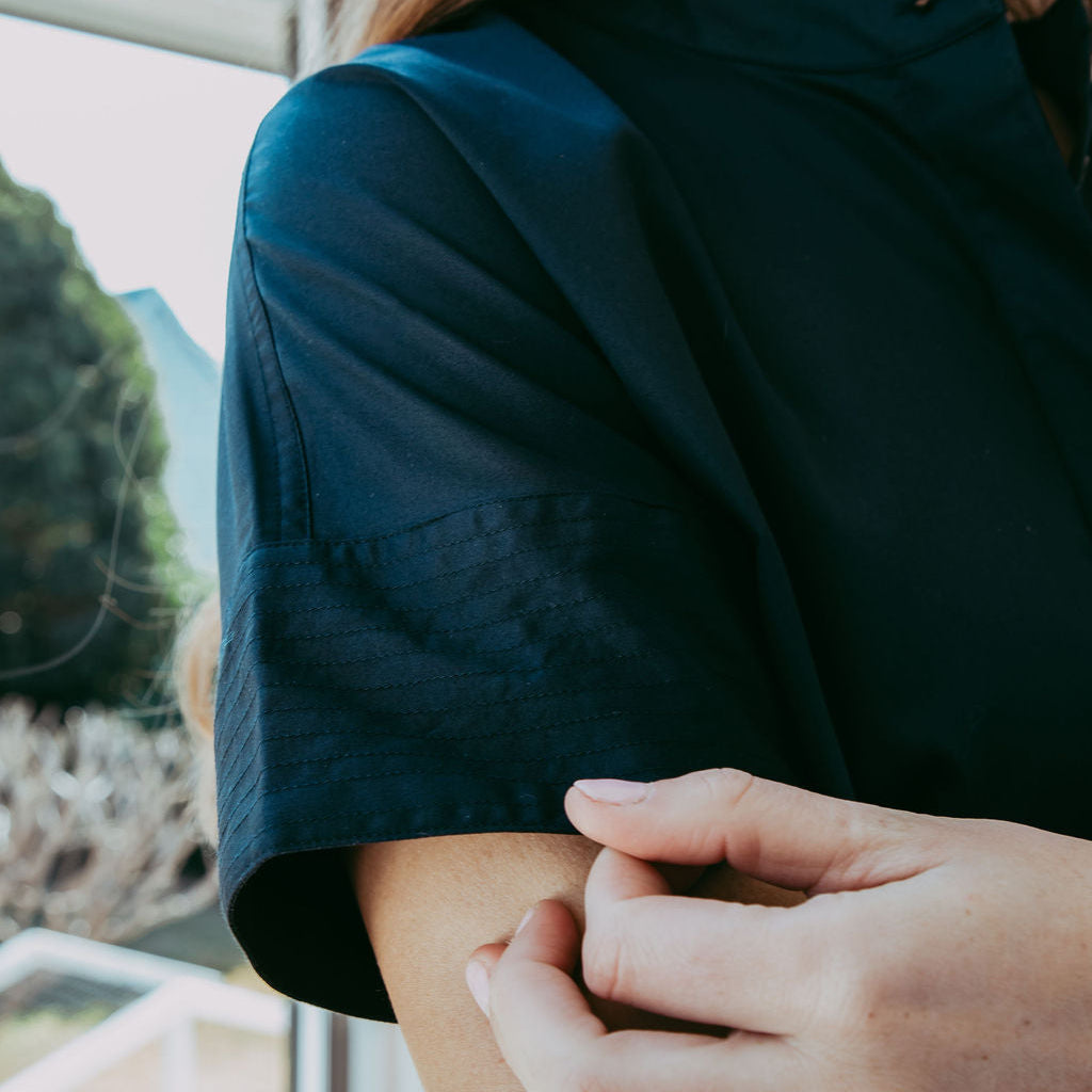 Person wearing a dark green shirt with a blurred outdoor background