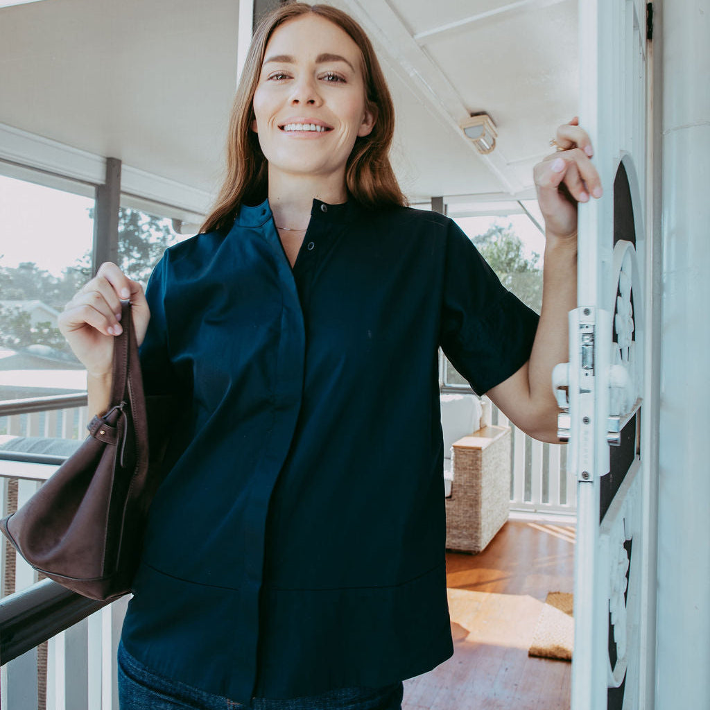Woman in a dark shirt standing on a porch with a blurred background