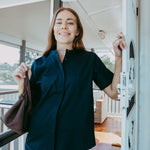 Woman in a dark shirt standing on a porch with a blurred background
