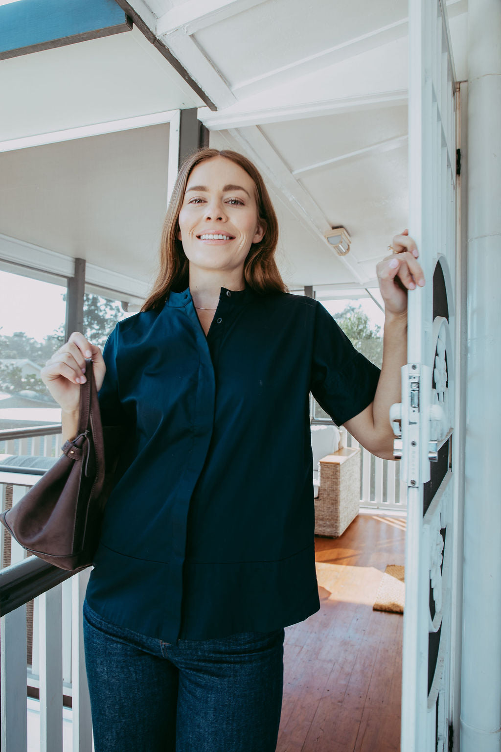Woman in a dark shirt standing on a porch with a blurred background