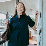Woman in a dark shirt standing on a porch with a blurred background