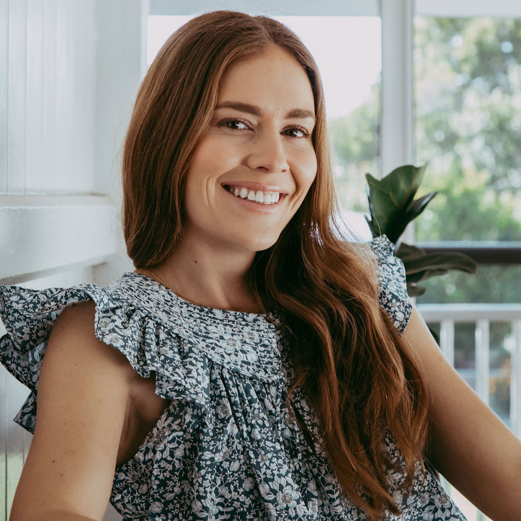 Woman with long brown hair smiling on a porch