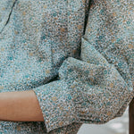 Close-up of a person wearing a floral dress with cuffed sleeves.