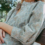 Person wearing a floral dress sitting outdoors with blurred background
