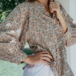 Woman wearing a floral blouse with a blurred natural background