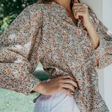 Woman wearing a floral blouse with a blurred natural background