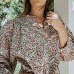 Person wearing a floral blouse with a blurred outdoor background