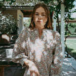 Woman standing outdoors under a canopy of greenery