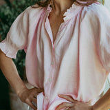 Woman wearing a light pink blouse with a blurred background