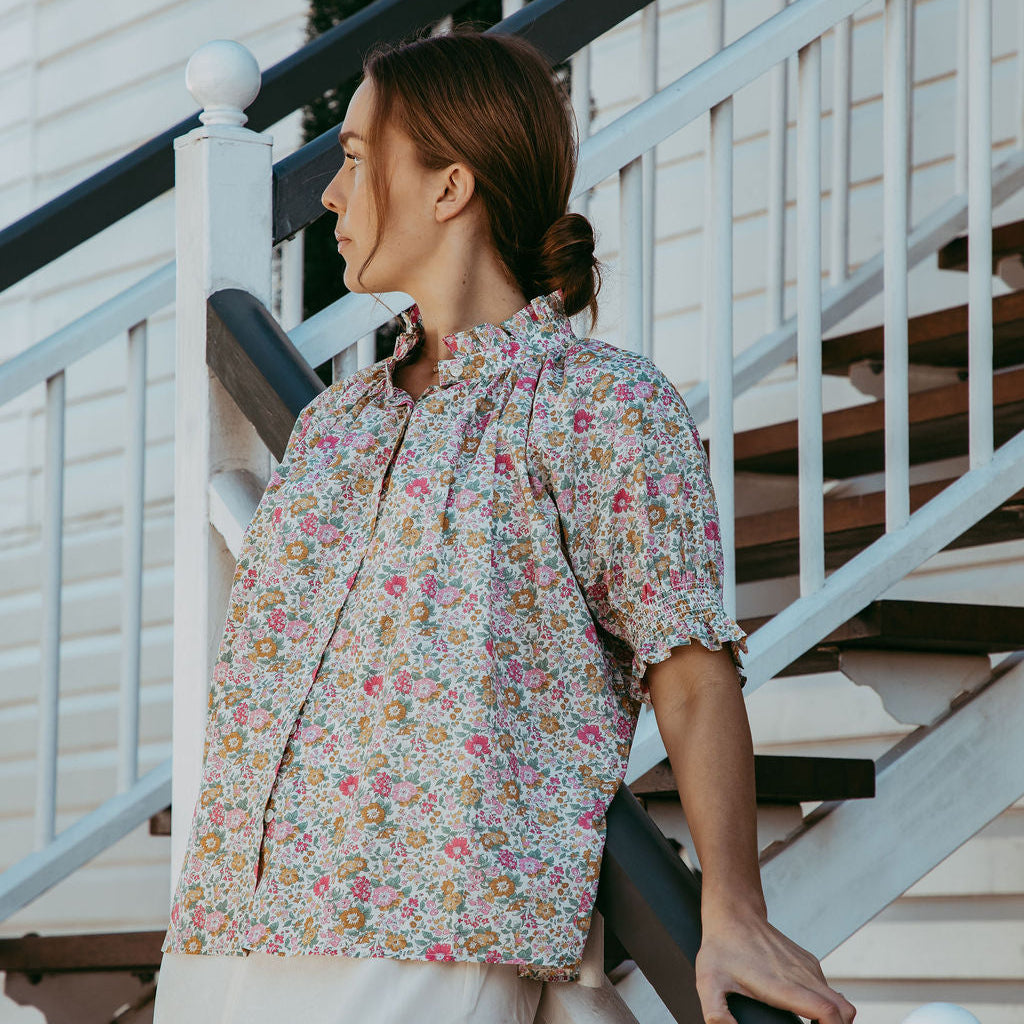 Woman in a floral blouse standing on a staircase
