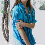 Woman wearing a blue shirt standing outdoors with blurred background