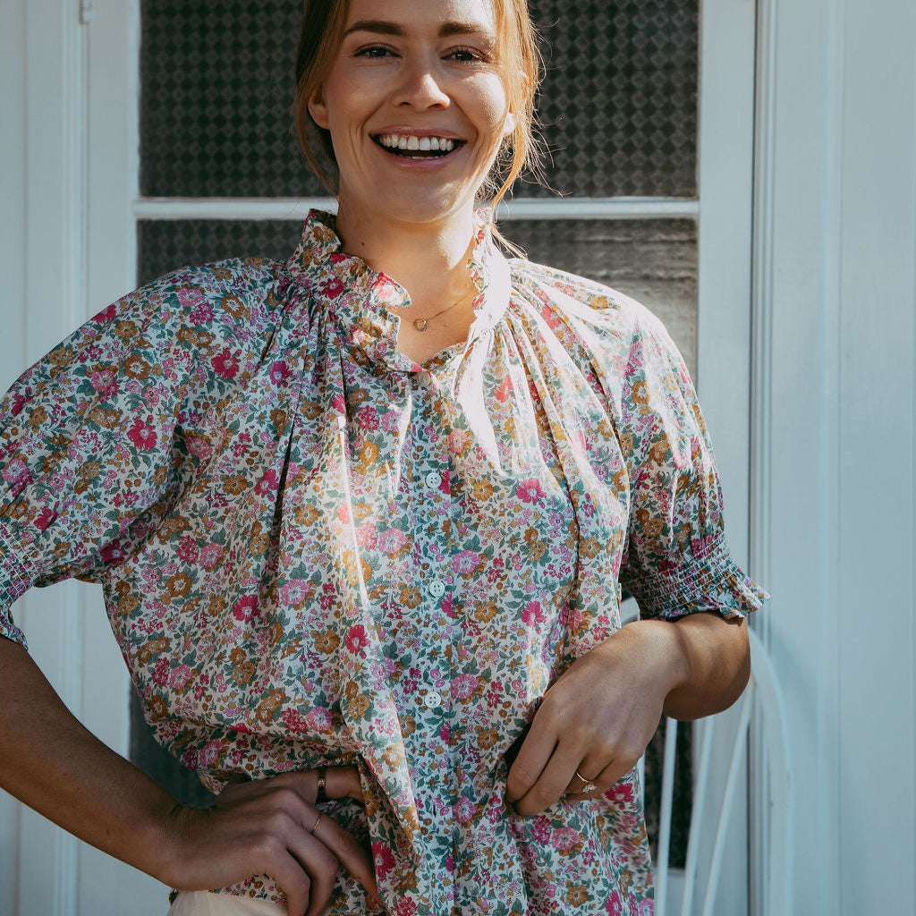 Woman wearing a floral dress standing in front of a white door.