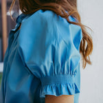 Woman wearing a blue blouse with smocked details.