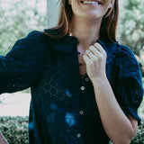 Woman wearing a dark blue blouse with floral patterns outdoors