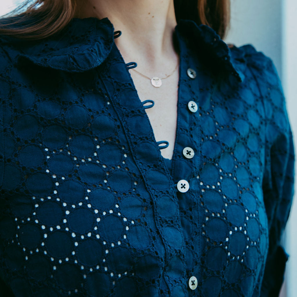 Navy blue lace blouse with button details worn by a person.