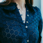 Navy blue lace blouse with button details worn by a person.