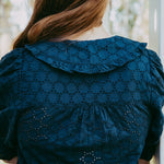 Person wearing a blue embroidered dress with a blurred background