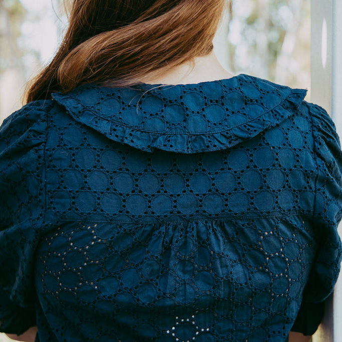 Person wearing a blue embroidered dress with a blurred background