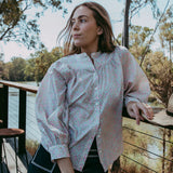 Woman standing by a lakeside with trees in the background