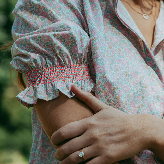 Person wearing a floral blouse with a blurred background
