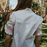 Person wearing a light blouse with ruffled sleeves in a forest setting