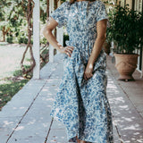 Woman in a floral dress standing on a porch with string lights