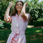 Woman in a pink dress swinging on a swing set with greenery in the background