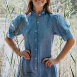 Woman in a blue dress standing among tall grasses