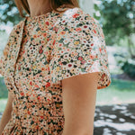 Woman wearing a floral dress with a blurred outdoor background