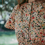 Person wearing a floral dress with a blurred natural background
