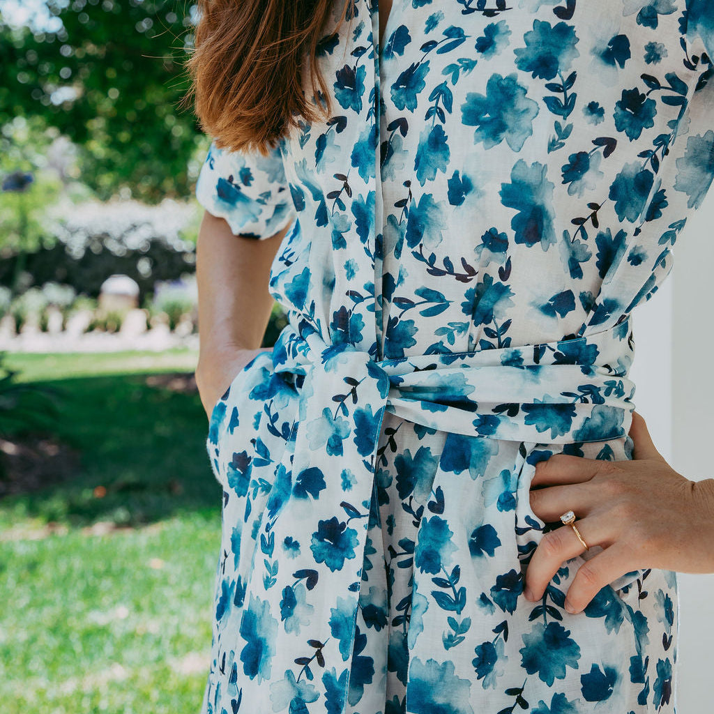 Person wearing a blue floral dress with a blurred outdoor background