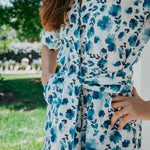 Person wearing a blue floral dress with a blurred outdoor background