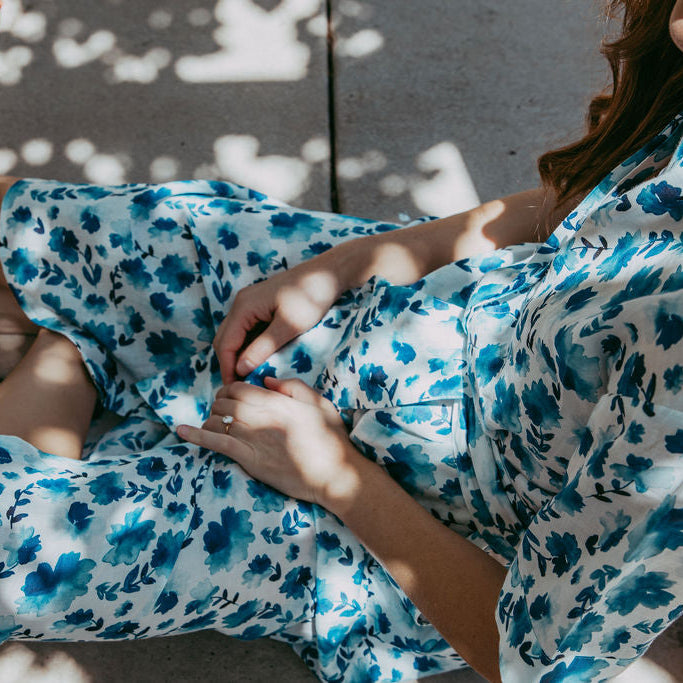 Person wearing a blue and white floral dress sitting on a tiled floor.