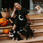 Woman with in a black dress with dogs on a staircase decorated with pumpkins and flowers