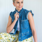 Close up of denim Vest with White stitching and pockets with buttons