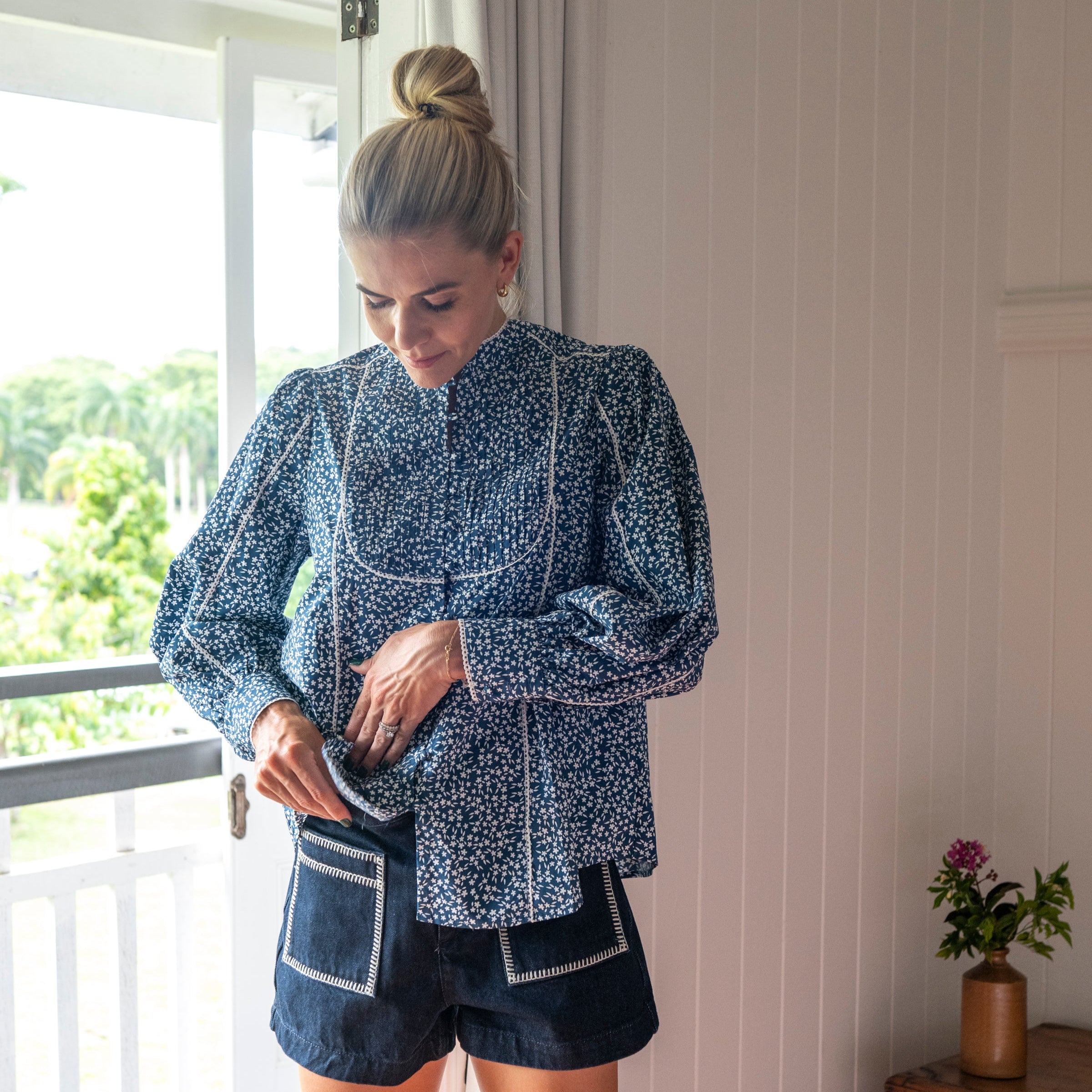 Navy Floral Shirt with white flowers and paired with denim shorts. With high neck tucked in