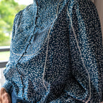 Close up of Navy floral blouse with white trim and covered buttons and high neck