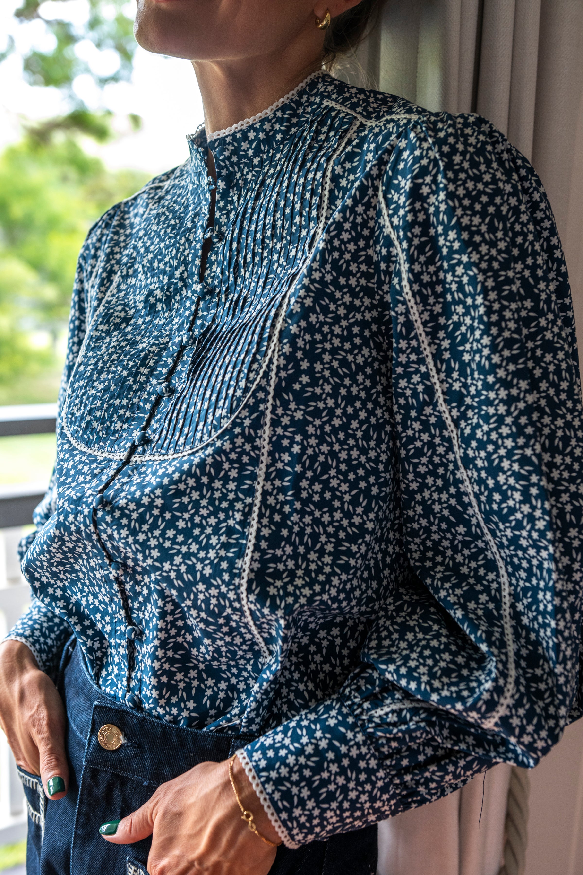 Close up of Navy floral blouse with white trim and covered buttons and high neck