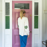 back view of heart patchwork sleeves on white denim jacket with pink door and denim jeans. Frill collar neckline