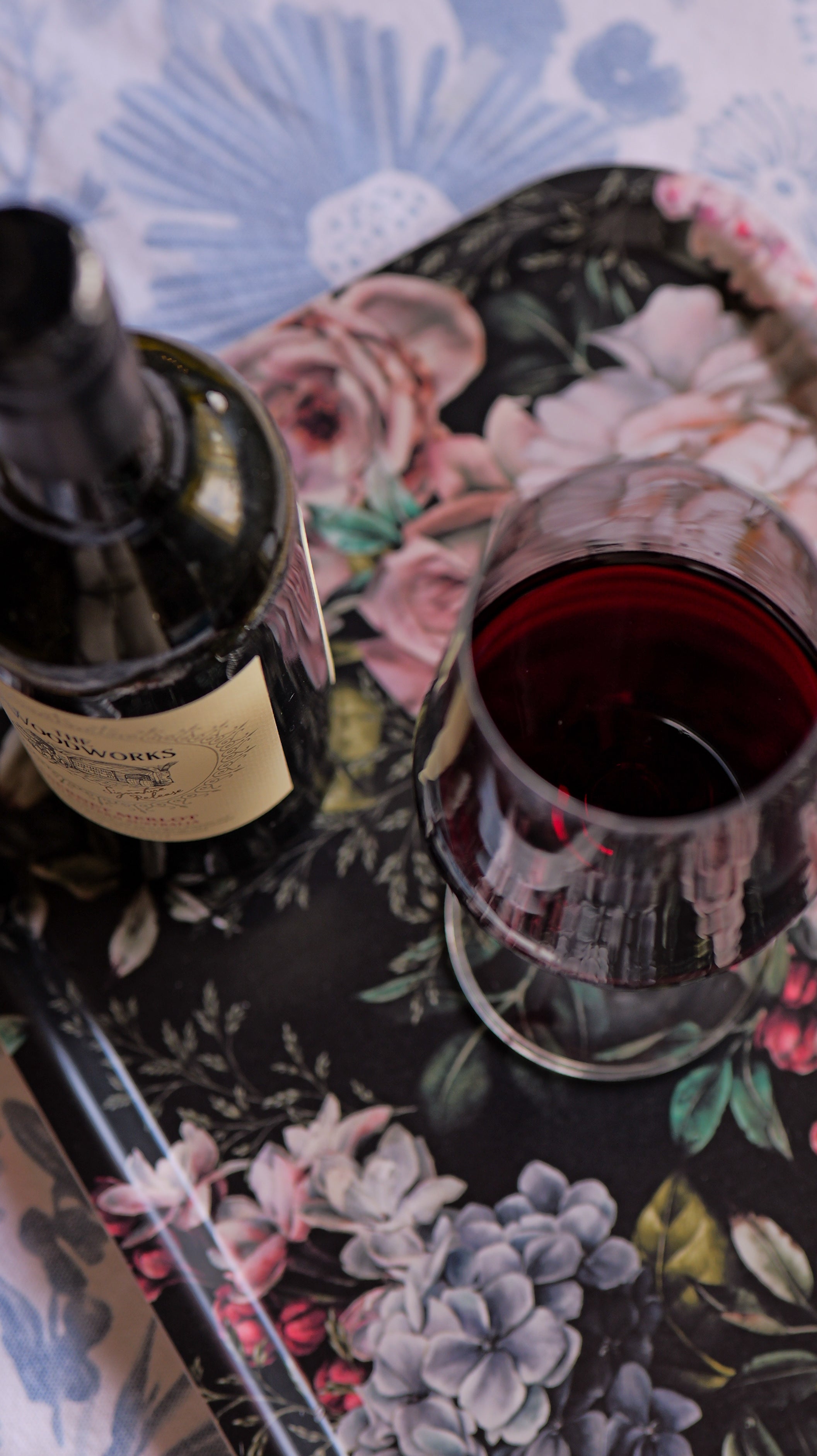 Wine bottle and glass on a floral tablecloth