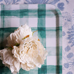 White flowers on a green and white checkered tray with a floral-patterned background