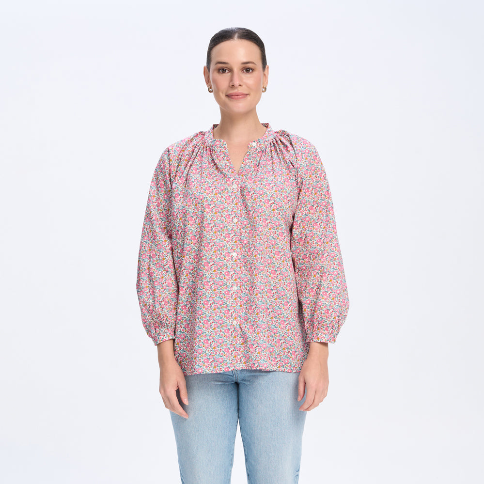 Woman wearing a patterned blouse and light blue jeans on a white background