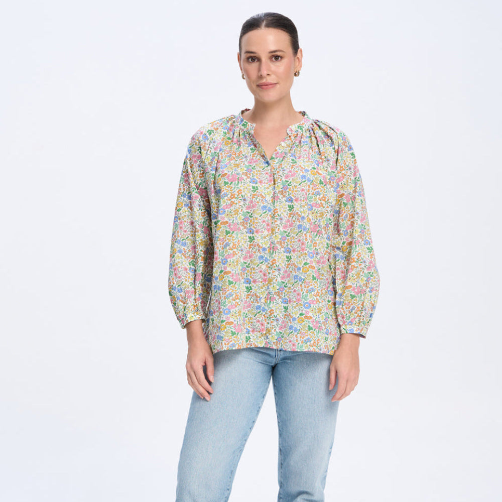 Woman wearing a floral blouse and light blue jeans on a white background