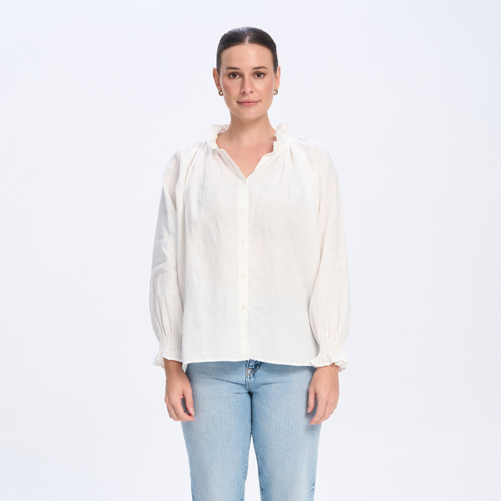 Woman wearing a white blouse and light blue jeans on a white background