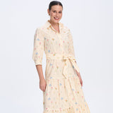 Woman wearing a long, light-colored dress with a floral pattern on a white background