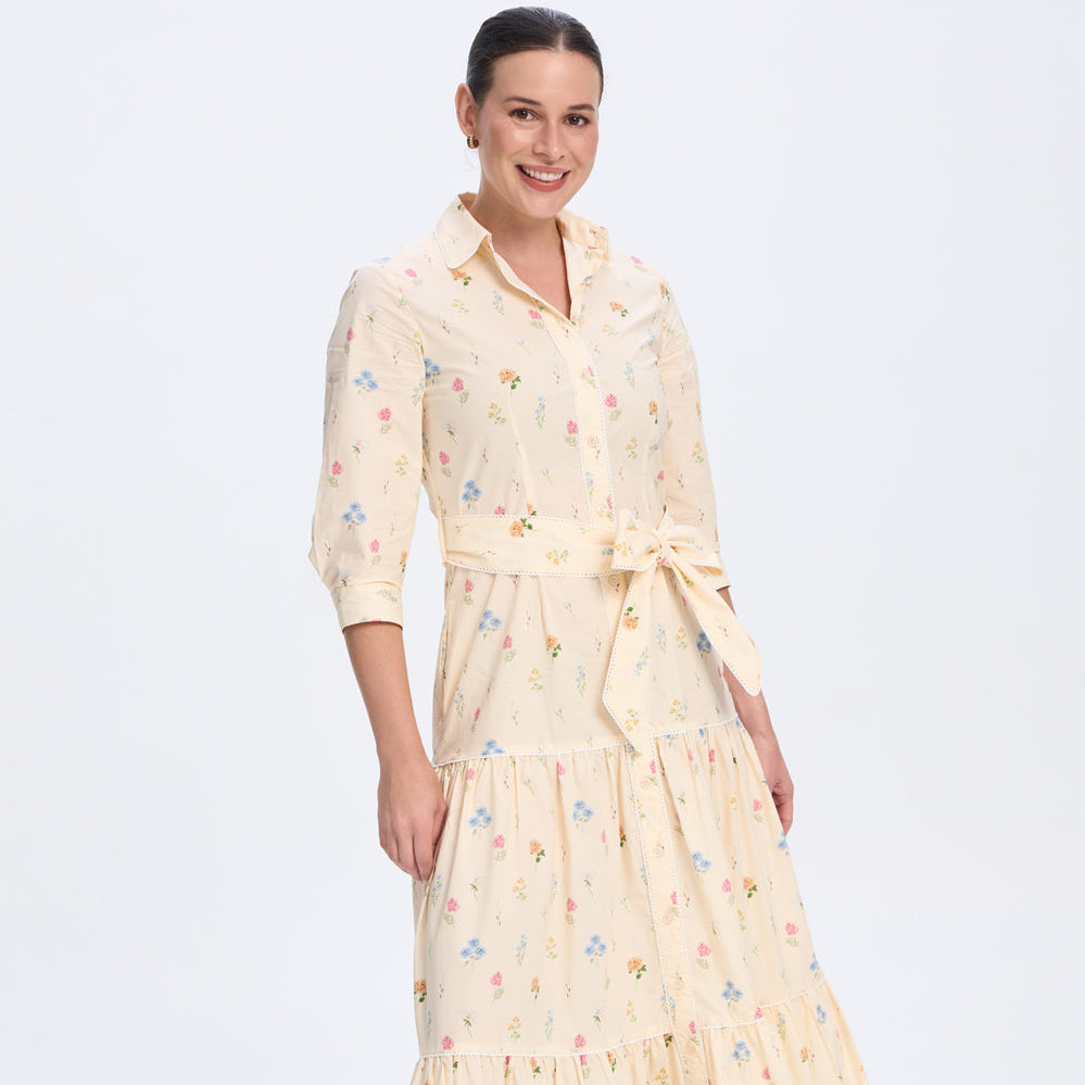 Woman wearing a long, light-colored dress with a floral pattern on a white background